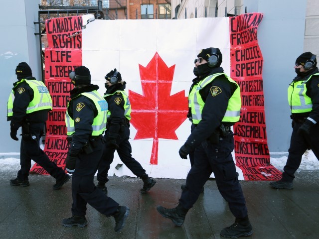 A group of police officers walk past a Canadian flag near Parliament Hill as demonstrators continue to protest the vaccine mandates implemented by Prime Minister Justin Trudeau on February 7, 2022 in Ottawa, Canada. - Canadian authorities struggled Monday to tackle a truckers' protest against Covid restrictions which has paralyzed the national capital for days and threatens to snowball into a full-blown political crisis for Prime Minister Justin Trudeau.