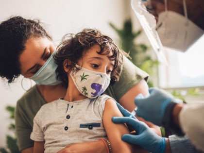 Child in mask receives COVID-19 vaccine. (jacoblund/iStock / Getty Images Plus)