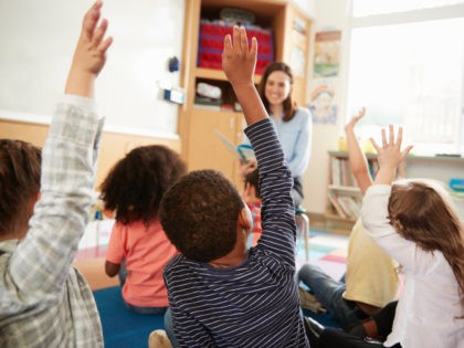 Children raising hands in school.