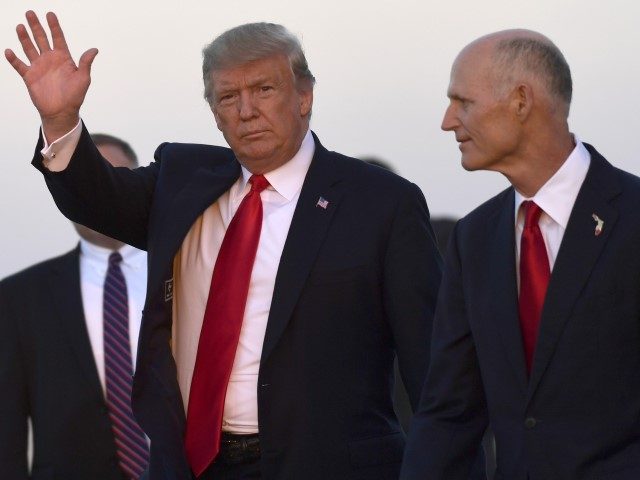 President Donald Trump, left, waves as he walks with Florida Gov. Rick Scott, right, after arriving on Air Force One at Southwest Florida International Airport in Fort Myers, Fla., Wednesday, Oct. 31, 2018. Trump is campaigning for Scott, who is challenging incumbent Democratic Sen. Bill Nelson for a seat in …