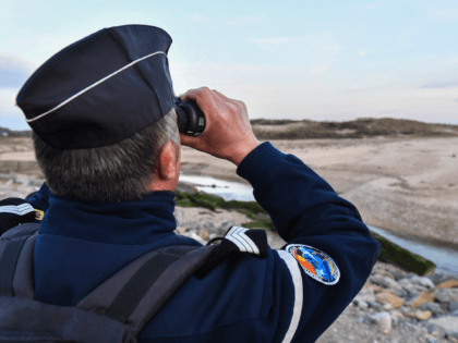 A French Gendarme looks through a pair of binoculars during a patrol of the beaches at Tardinghen near the northern port city of Calais on April 4, 2019. - Since the end of October 2018, the French and British authorities have been facing an upsurge in illegal Channel crossings from …