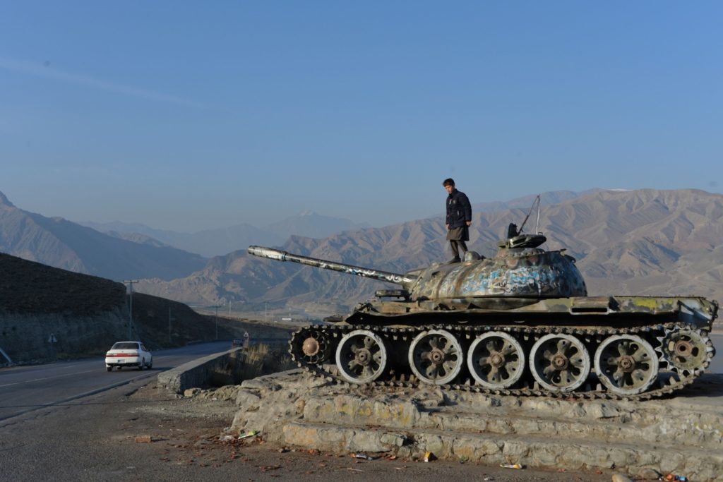 TOPSHOT - This photo taken on November 28, 2019 shows an Afghan boy playing on the wreckage of a Soviet-era tank alongside a road on the outskirts of Kabul. - December 2019 marks the 40th anniversary of the Soviet Union's "intervention" -- or invasion -- of Afghanistan. In the decades since the war, which ended in 1989, Afghan veterans like Shah Sulaiman and former Soviet soldiers have had to grapple with the physical and emotional wounds of a bloody conflict whose purpose and consequences remain angrily contested. (Photo by NOORULLAH SHIRZADA / AFP) / TO GO WITH 'AFGHANISTAN-CONFLICT-USSR-RUSSIA-ANNIVERSARY',FOCUS BY MUSHTAQ MOJADDIDI and MARINA LAPENKOVA (Photo by NOORULLAH SHIRZADA/AFP via Getty Images)