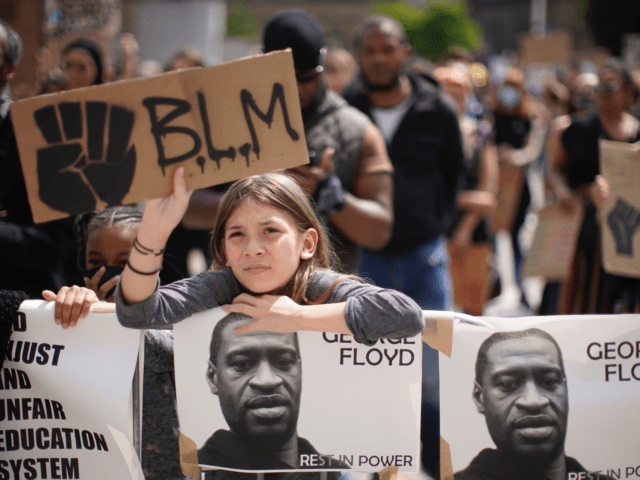 LEEDS, ENGLAND - JUNE 14: A young girl holds up a "BLM" sign during a Black Lives Matter rally in Millennium Square on June 14, 2020 in Leeds, England. Black Lives Matter Rallies continue across the UK following the death on 25 May 2020 of an African American man, George ...
