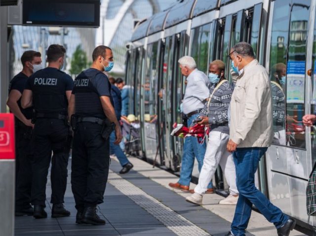 German police officers stand on a platform as French passengers step out of the tram at a