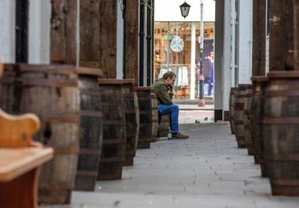 A ma sits outs side a closed-down pub in Belfast on November 27, 2020, as stricter restrictions come in to force to help stem the spread of the novel coronavirus. - Northern Ireland shops, pubs and restaurants will shut for two weeks in efforts to curb the coronavirus, the British …