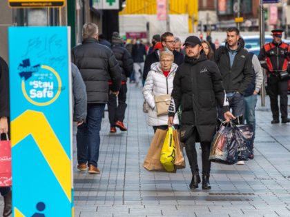 Shoppers walk through Belfast city centre on Christmas Eve, December 24, 2020 as the Province prepares to go into a six week lockdown. - Fears over new strains and surging coronavirus infections in general across Europe have severely dampened the mood over the holiday season. (Photo by Paul Faith / …