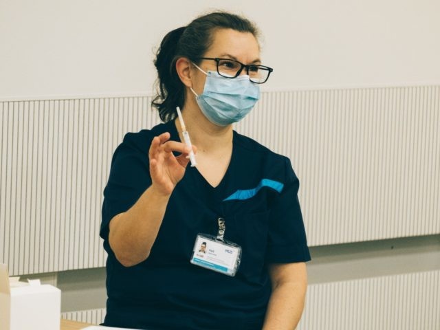 A health operator of the Helsinki University Hospital holds a syringe with the Pfizer-Bion