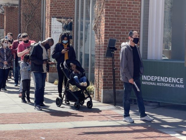 Tourists wearing face masks wait in line outside the Liberty bell building in Philadelphia