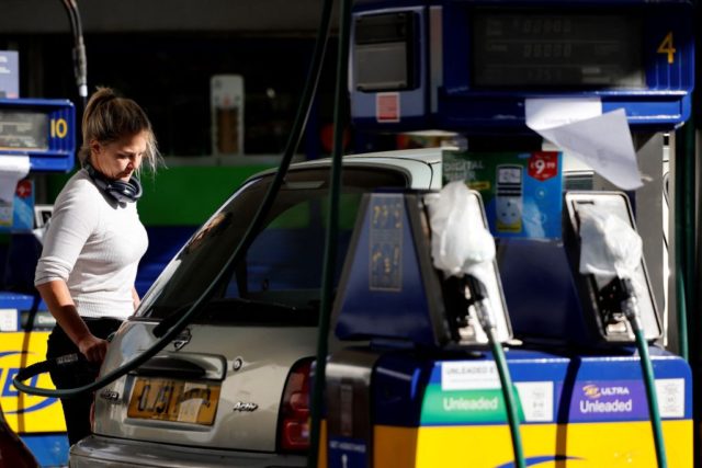 A motorist refills the fuel tanks of their vehicle, opposite tapped-off petrol and diesel