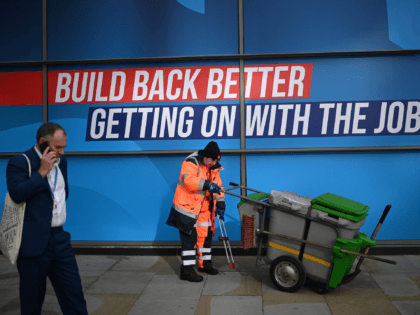 A delegate passes a street cleaner on the second day of the annual Conservative Party Conference being held at the Manchester Central convention centre in Manchester, northwest England, on October 4, 2021. (Photo by Oli SCARFF / AFP) (Photo by OLI SCARFF/AFP via Getty Images)