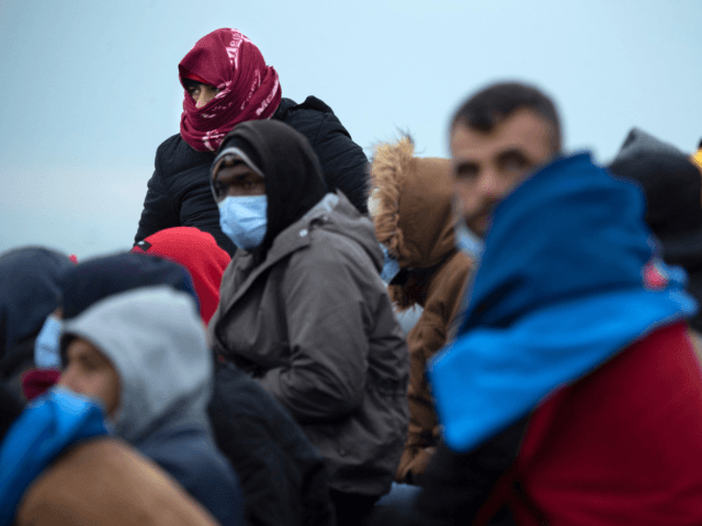 Migrants wait together on a beach in Dungeness on the south-east coast of England on November 24, 2021, after being rescued while crossing the English Channel. - The past three years have seen a significant rise in attempted Channel crossings by migrants, despite warnings of the dangers in the busy …