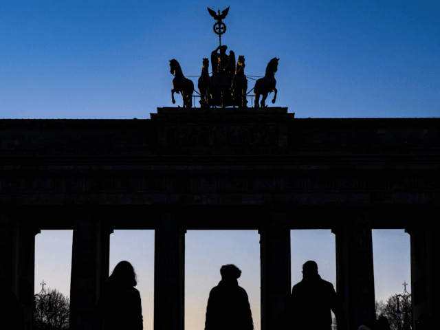 Tourists are silhouetted against Berlin's Brandenburg Gate as it catches the last rays of