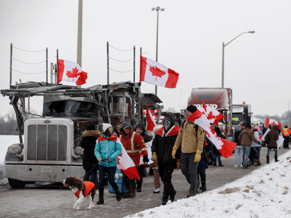 Supporters for a convoy of truckers driving from British Columbia to Ottawa in protest of a Covid-19 vaccine mandate for cross-border truckers, gather near a highway overpass outside of Toronto, Ontario, Canada, on January 27, 2022. - A convoy of truckers started off from Vancouver on January 23, 2022 on …