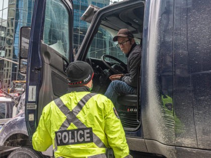 OTTAWA, ON - JANUARY 31: A police officer speaks with a trucker blocking the street on January 31, 2022 in Ottawa, Canada. Thousands turned up over the weekend to rally in support of truckers using their vehicles to block access to Parliament Hill, most of the downtown area Ottawa, and …
