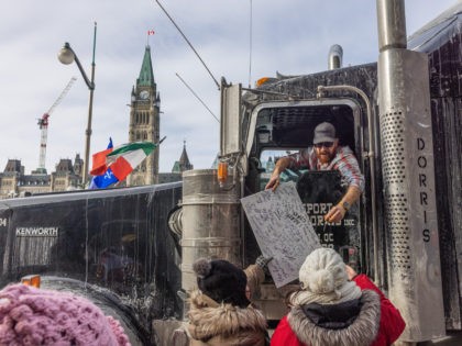 OTTAWA, ON - JANUARY 30: Trucker signs a protestors sign during a rally against COVID-19 o