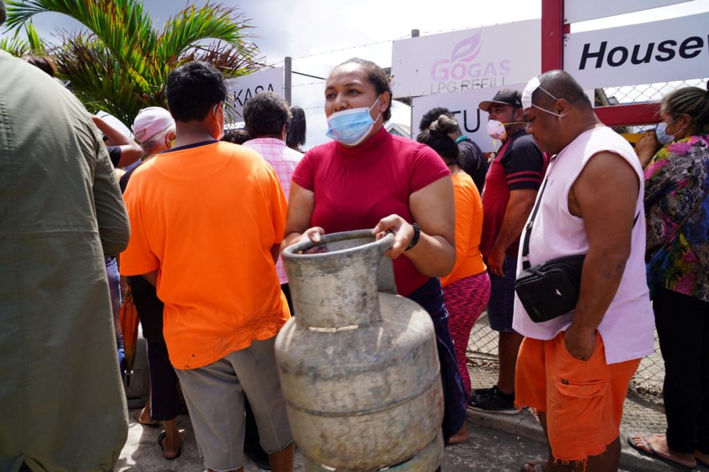 A woman (C) carries a refilled gas container in the centre of the capital Nuku'alofa ahead of the country's first lockdown on February 2, 2022, after Covid-19 was detected in the previously virus-free Pacific kingdom as it struggles to recover from the deadly January 15 volcanic eruption and tsunami. (Photo by Mary Lyn FONUA / Matangi Tonga / AFP) (Photo by MARY LYN FONUA/Matangi Tonga/AFP via Getty Images)