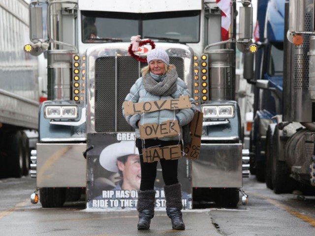 A protester stands in front of parked trucks as demonstrators continue to protest the vacc