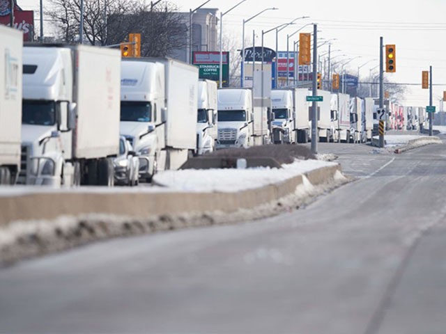 TOPSHOT - A line of trucks waits for the road to the Ambassador Bridge border crossing in Windsor, Ontario to reopen February 8, 2022, after protesters blocked the road Monday night. - The protestors supporting the Truckers Convoy in Ottawa blocked traffic in the Canada bound lanes since Monday evening. …