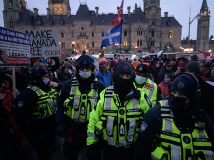 Police officers walk away from demonstrators during a protest by truck drivers over pandemic health rules and the Trudeau government, outside the parliament of Canada in Ottawa on February 11, 2022. - Canada's Ontario province Friday declared a state of emergency over the trucker-led protests paralyzing the capital and blocking …