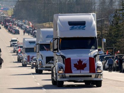 TOPSHOT - Trucks displaying the Canadian national flag drive by as anti-vaccine mandate and anti-government protesters demonstrate on Highway 15 near the Pacific Highway Border Crossing on the US-Canada border with Washington State in Surrey, British Columbia, Canada on February 12, 2022. (Photo by Jason Redmond / AFP) (Photo by …