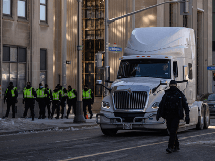 Police officers walk before a truck making its way along the central Wellington street, during a protest by truck drivers over pandemic health rules and the Trudeau government, outside the parliament of Canada in Ottawa on February 14, 2022. (Photo by Ed JONES / AFP) (Photo by ED JONES/AFP via …