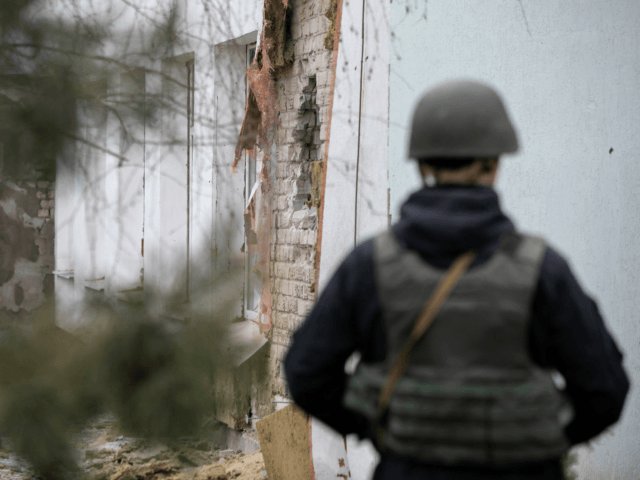 A Ukrainian soldier stands next to a damaged wall after the reported shelling of a kinderg