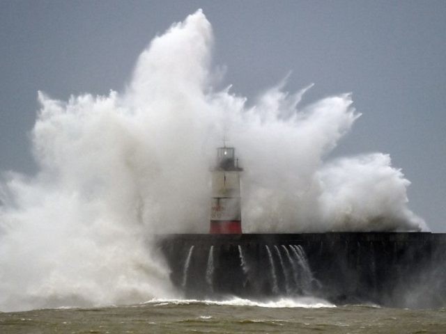 Waves crash over Newhaven Lighthouse and the harbour wall in Newhaven, southern England on