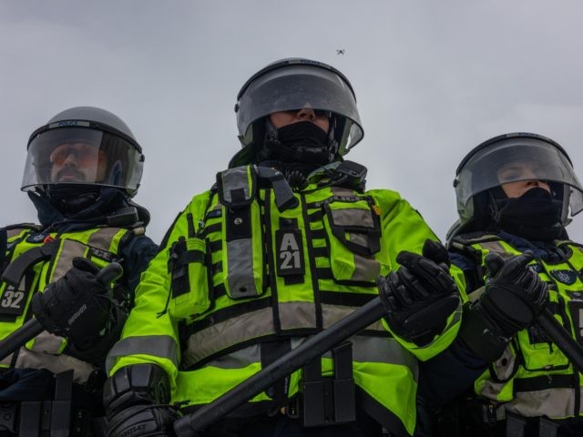 OTTAWA, ONTARIO - FEBRUARY 19: Police stand guard during a protest organized by truck drivers opposing vaccine mandates on February 19, 2022 in Ottawa, Ontario. The drivers have used vehicles to form a blockade that has blocked several streets near Parliament Hill. Prime Minister Justin Trudeau has invoked the Emergencies …
