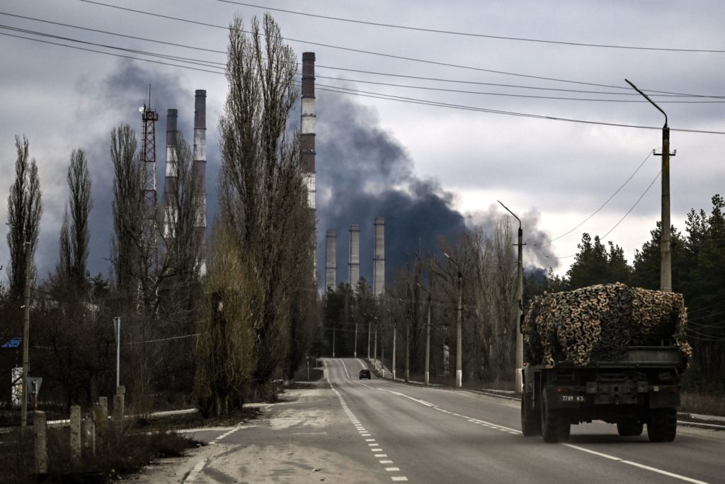 A military vehicle drives on a road as smoke rises from a power plant after shelling outside the town of Schastia, near the eastern Ukraine city of Lugansk, on February 22, 2022, a day after Russia recognised east Ukraine's separatist republics and ordered the Russian army to send troops there as "peacekeepers." - The recognition of Donetsk and Lugansk rebel republics effectively buries the fragile peace process regulating the conflict in eastern Ukraine, known as the Minsk accords. Russian President recognised the rebels despite the West repeatedly warning him not to and threatening Moscow with a massive sanctions response. (Photo by Aris Messinis / AFP) (Photo by ARIS MESSINIS/AFP via Getty Images)