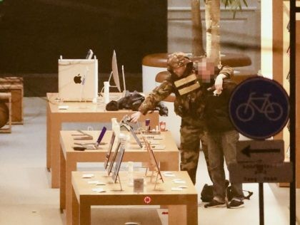 An hostage-taker puts his arm around the neck of an hostage during a robbery at the Apple Store on Leidseplein in Amsterdam on February 22, 2022. - A man with a firearm was in the vicinity of an Amsterdam shop, police in the Netherlands said February 22, 2022 adding that …