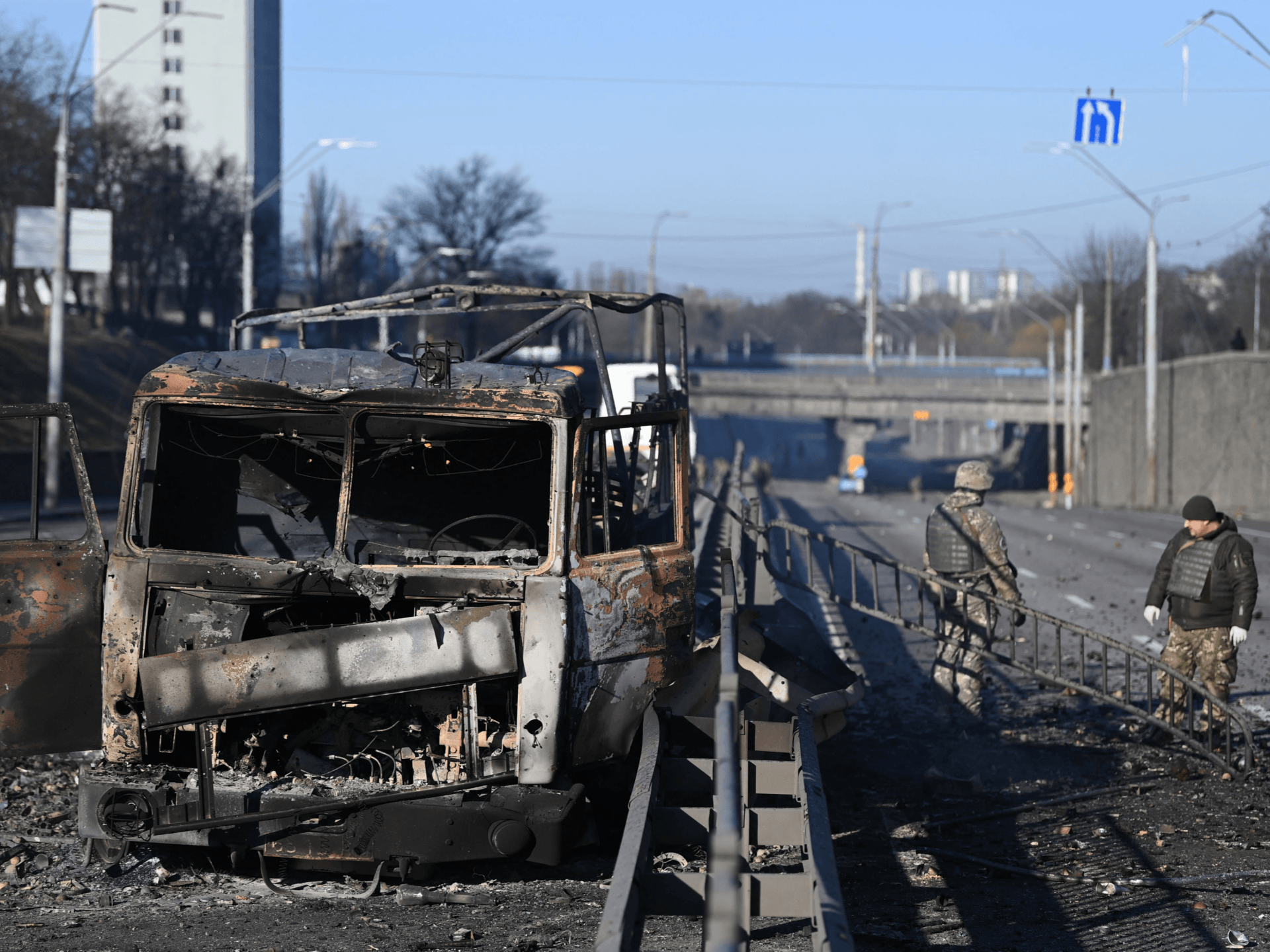 TOPSHOT - Ukrainian soldiers stand past a burnt Ukrainian army vehicle on the west side of the Ukrainian capital of Kyiv on February 26, 2022. - Ukrainian soldiers beat back a Russian attack in the capital Kyiv only hours after President Volodymyr Zelensky warns Moscow would attempt to take the city before dawn. (Photo by Daniel LEAL / AFP) (Photo by DANIEL LEAL/AFP via Getty Images)