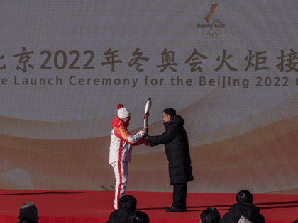China's Vice Premier Han Zheng, right, passes the torch to former Chinese World Speed Skating Champion Luo Zhihuan during the first leg launch ceremony for the Beijing 2022 Winter Olympics Torch Relay in front of the Olympic Tower outside of the closed loop bubble on February 2, 2022 at Olympic …