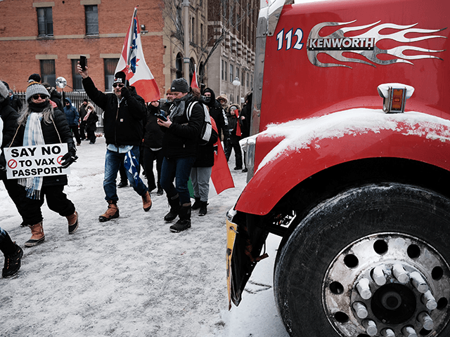 People gather along with truck drivers to block the streets during an anti-government and anti-vaccine mandate protest on February 12, 2022 in Ottawa, Ontario, Canada. The protest has entered the 16th day of blockading the area around the Parliament building in Canada’s capital. Thousands of protestors and hundreds of vehicles are expected to join the convoy which has forced businesses to close and unnerved residents. A state of emergency has been called in Ottawa as police and local officials decide on how best to bring the event to an end. (Photo by Spencer Platt/Getty Images)