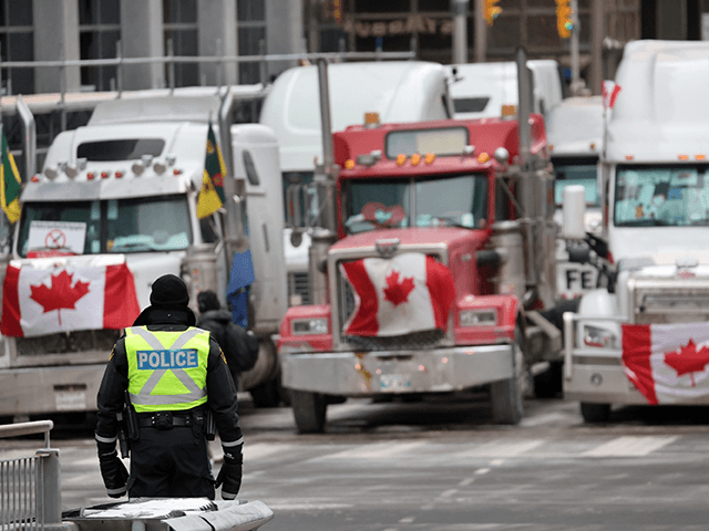 A police officer stands guard near trucks participating in a blockade of downtown streets