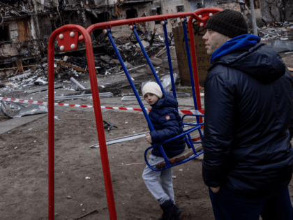 KYIV, UKRAINE - FEBRUARY 25: A boy plays on a swing in front of a damaged residential block hit by an early morning missile strike on February 25, 2022 in Kyiv, Ukraine. Yesterday, Russia began a large-scale attack on Ukraine, with Russian troops invading the country from the north, east …
