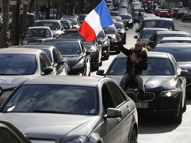 Non-licensed private hire cab drivers, one waving a French flag, stage a protest in Paris