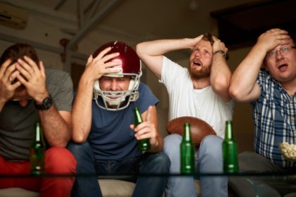 Four friends watching american football game on television, feeling frustrated, emotional distress, throwing popcorn, shouting