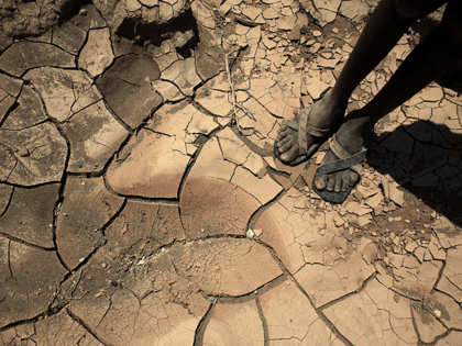 A young boy from the remote Turkana tribe in Northern Kenya stands on a dried up river bed