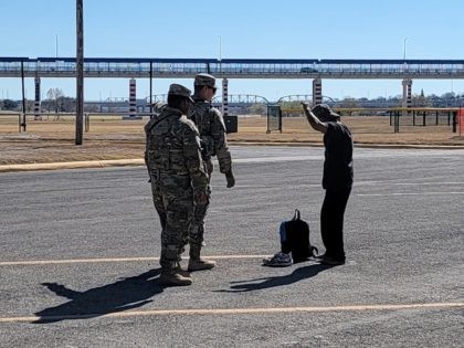 Texas National Guardsmen apprehend a migrant after he illegally crossed the Rio Grande in Eagle Pass, Texas, under Operation Lone Star. (Bob Price/Breitbart Texas)