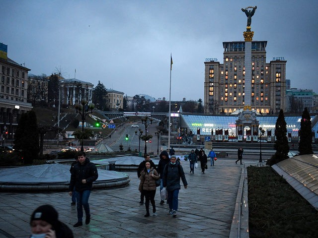 People walk in central Kyiv in front of the Independence Monument early on February 24, 20