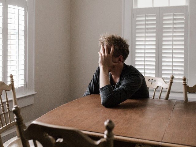 Man Leaning on Wooden Table