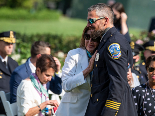 Speaker of the House Nancy Pelosi hugs Capitol Police Officer Michael Fanone during an eve