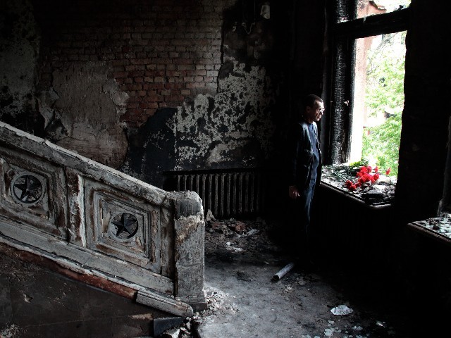 In this Sunday May 4, 2014 file photo, a man lays flowers inside the burnt trade union building in Odessa, Ukraine. Demonstrators have gathered in the Ukrainian city of Odessa to mark the second anniversary of the street clashes that culminated in a fire that killed 43 people as they took shelter from opponents. (AP Photo/Sergei Poliakov)