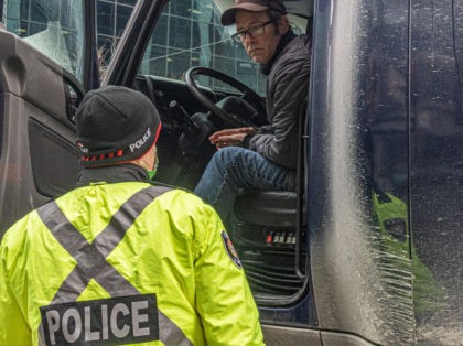 A police officer speaks with a trucker blocking the street on January 31, 2022 in Ottawa, Canada. Thousands turned up over the weekend to rally in support of truckers using their vehicles to block access to Parliament Hill, most of the downtown area Ottawa, and the Alberta border in hopes …