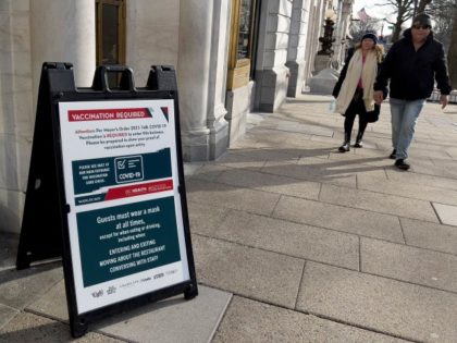 A sign requiring proof of vaccination for guests is posted outside a restaurant in downtow