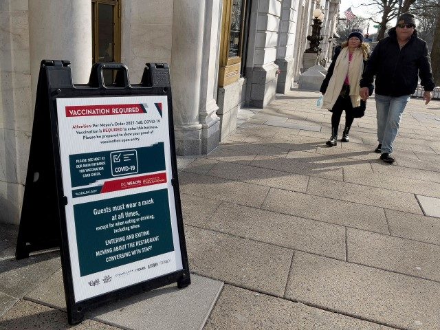 A sign requiring proof of vaccination for guests is posted outside a restaurant in downtown Washington DC, January 19, 2022.