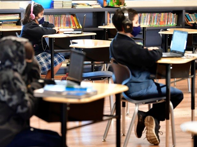 Students sit with their laptop computers at St. Joseph Catholic School in La Puente, Calif