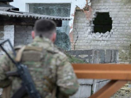 A Ukrainian soldier looks at debris after the reported shelling of a kindergarten in the settlement of Stanytsia Luhanska, on February 17, 2022. (Photo by Aleksey Filippov/AFP via Getty Images)