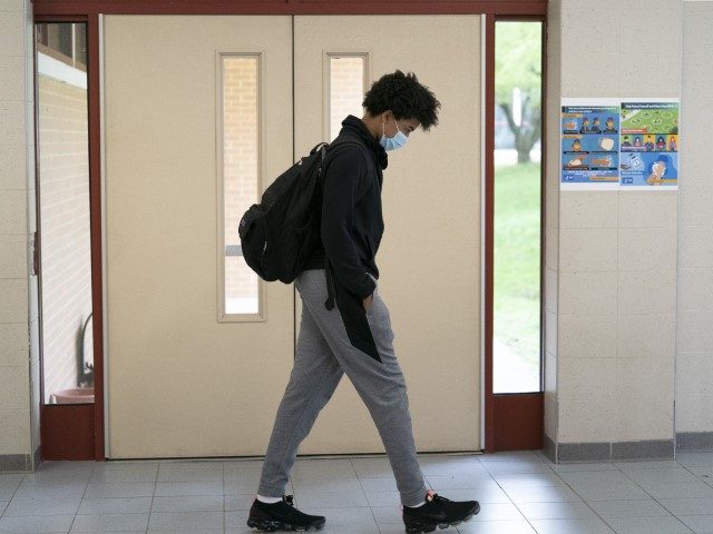 A White Plains High School student walks between classes, Thursday, April 22, 2021, in White Plains, N.Y. Secretary of Education Miguel Cardona visited the school as part of the 'Help is Here' tour. The school reopened to all students on April 12.