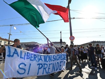 People hold a banner reading a banner " Liberty dont ask, on take" as they demonstrate aga